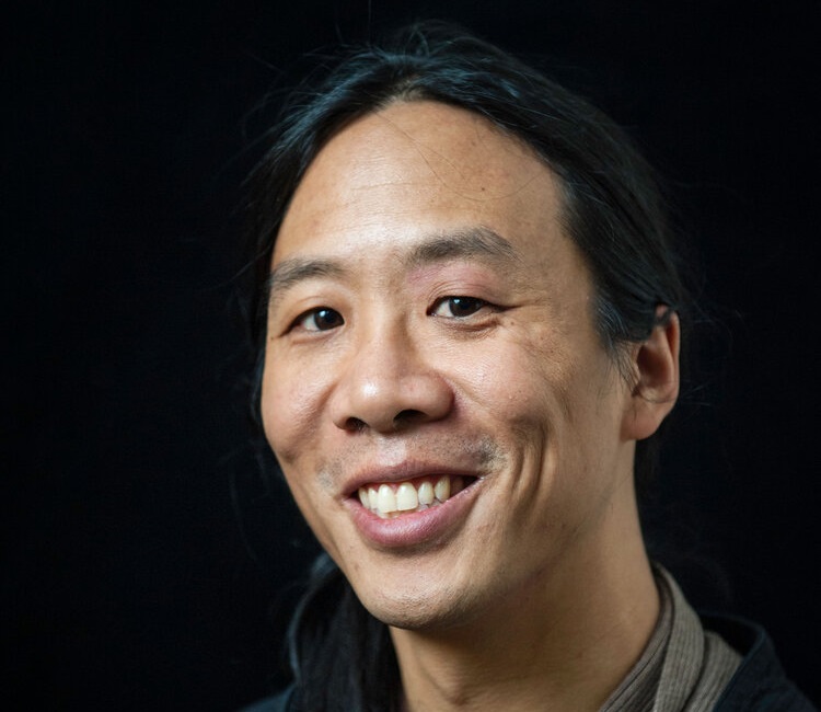 Andrew is an Asian male wearing a red shirt under a black jacket.
