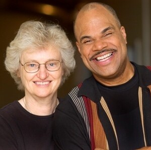 Anita is a white female wearing a black shirt and T. Mychael is a black male wearing a striped shirt.