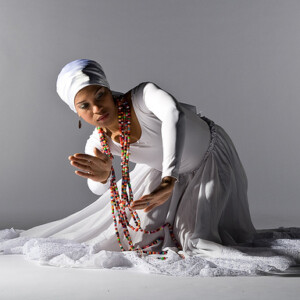 Djenane is a black woman wearing a white dress.