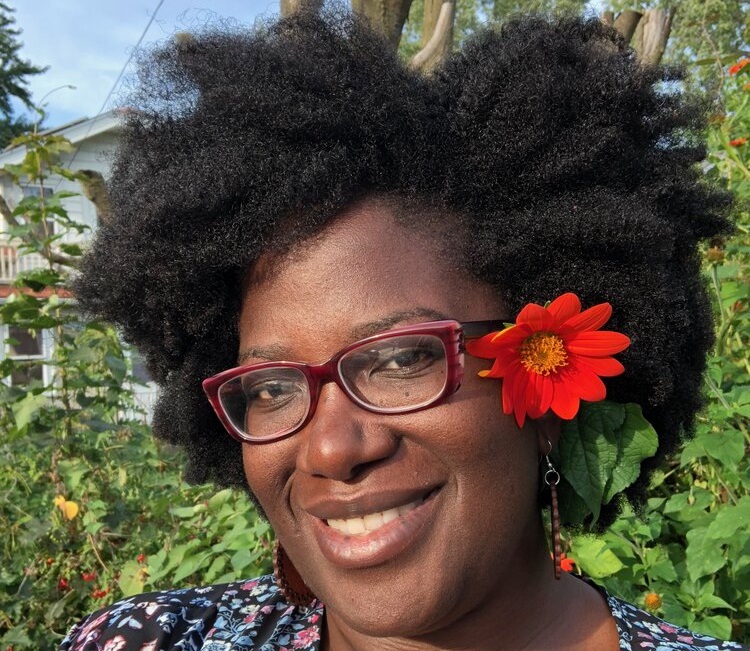 Kashimana is a black female wearing a flowered shirt.