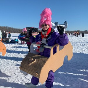 Jan is a white female wearing a pink hat and purple snowsuit.