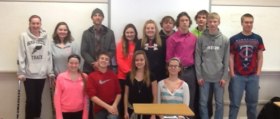 Kristoff is standing with a group of students in a classroom.