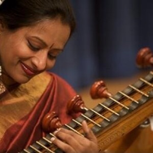Nirmala is an Indian woman wearing a traditional dress playing her instrument.