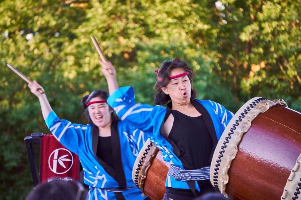 The TaikoArts Midwest performers are wearing black shirts under blue robes.