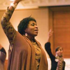 Yvette is a Black woman standing up and speaking an event.