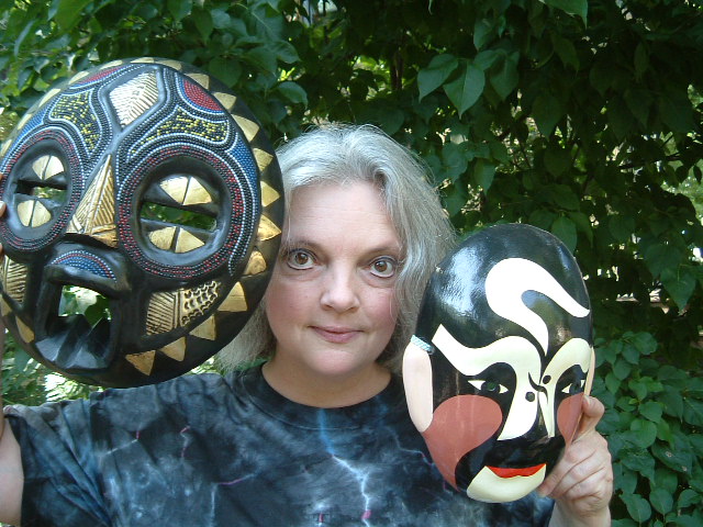 Rhonda is a white woman holding two theatrical masks up next to her own face.
